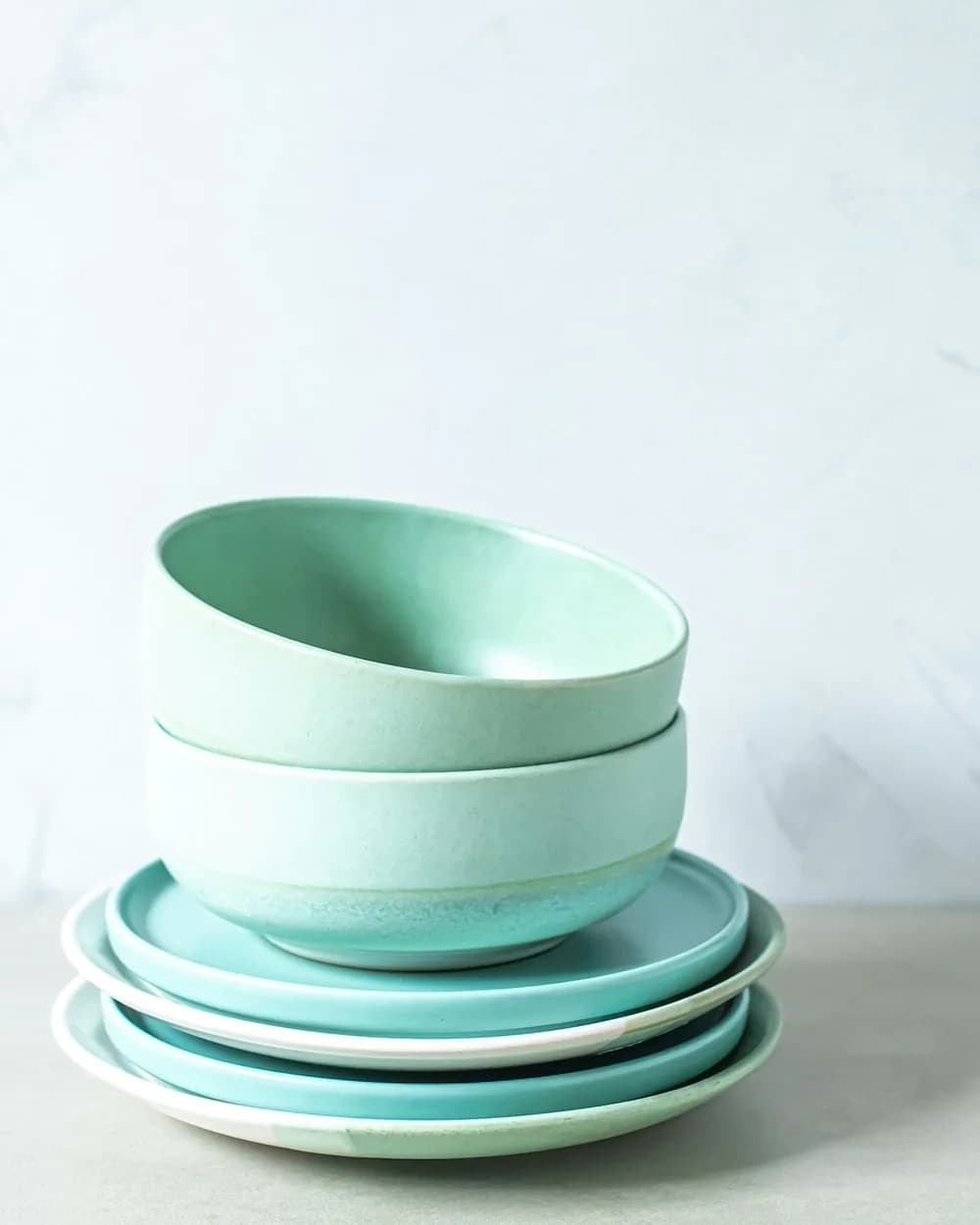 Seafoam stoneware bowls stacked on matching plates